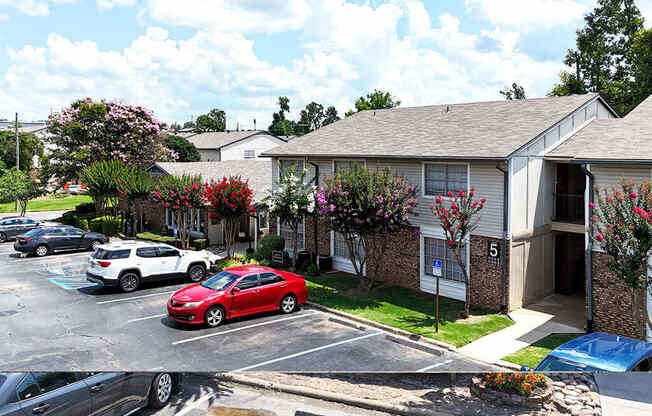 A red car is parked in a parking lot in front of a building with the number 5 on it.