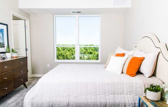 Inviting apartment bedroom with expansive nature views, featuring spacious walk-in closets and the comfort of central heating and air conditioning.
