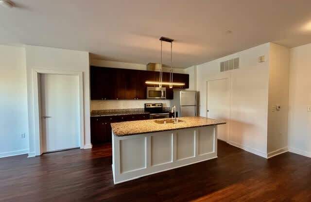 A kitchen with a granite countertop and a hanging light fixture.