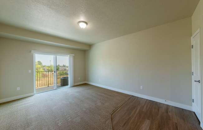 an empty living room with a door leading to a balcony