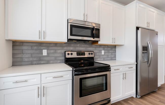 a kitchen with white cabinets and stainless steel appliances