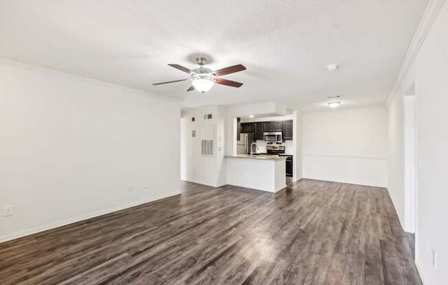 A room with a ceiling fan and wooden flooring.