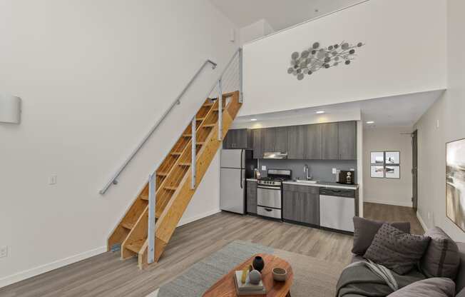 a living area with a staircase and a kitchen in the background