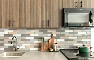 A kitchen with a sink, stove, and wooden cabinets.