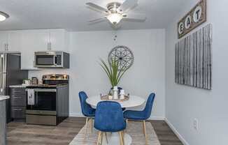 an open kitchen and dining area with a table and chairs and a ceiling fan