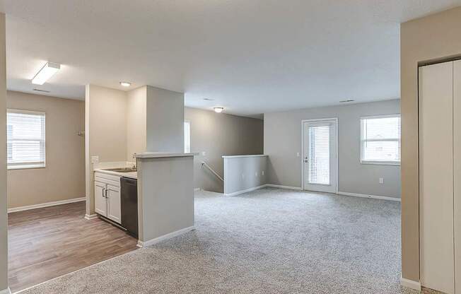 A spacious living room with a kitchenette and a staircase.