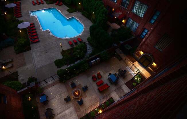 A pool surrounded by red chairs and umbrellas.