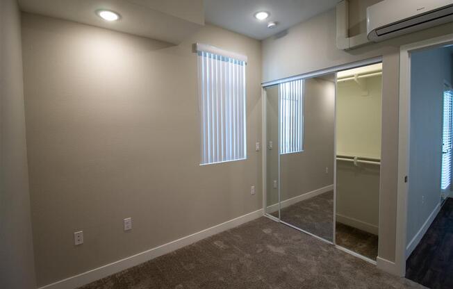 a bedroom with a large window and a mirrored closet at Loma Villas Apartments, California