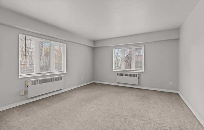 A room with a carpeted floor and two windows.