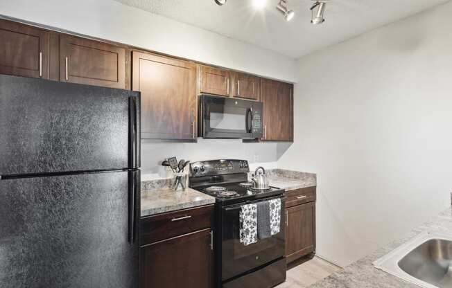 an apartment kitchen with black appliances and wood cabinets