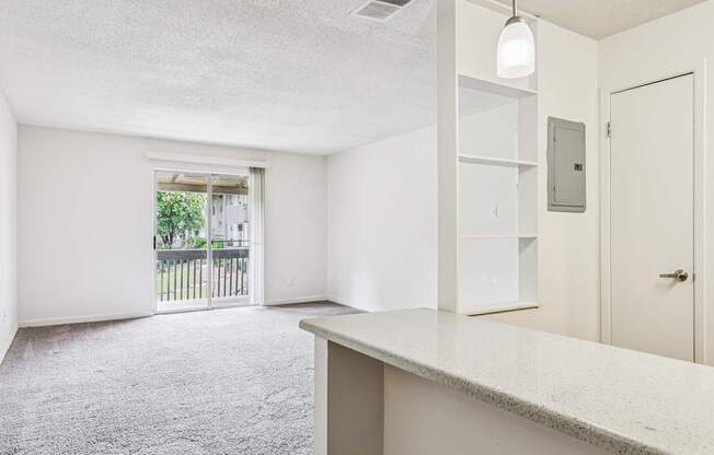 A white room with a carpeted floor and a door leading to a balcony.