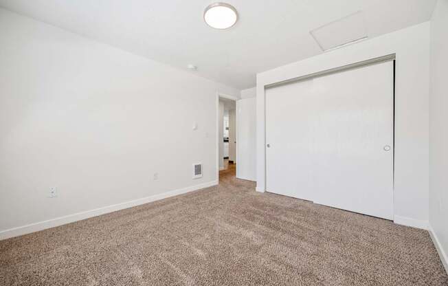 A large, empty room with a carpeted floor and a white door.