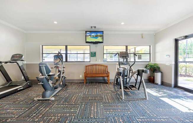A gym with treadmills, exercise bikes, and a television.