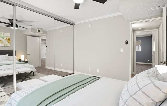 Carpeted bedroom with ceiling fan and large mirrored closet.