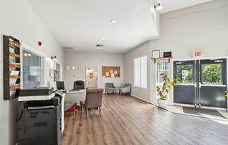 an office space with a desk and a refrigerator and a glass door