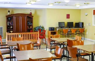 A room with tables and chairs and a bookcase.
