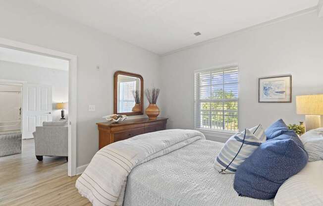 A bedroom with a large bed and a mirror on the dresser.