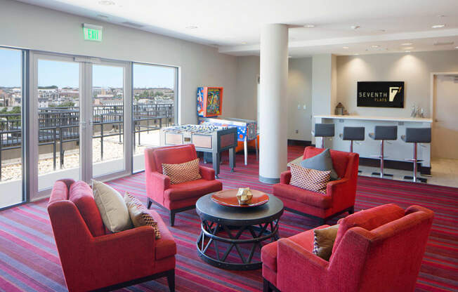 a living room with red chairs and a bar and a balcony