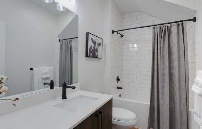A bathroom with a white countertop and a white tiled wall.