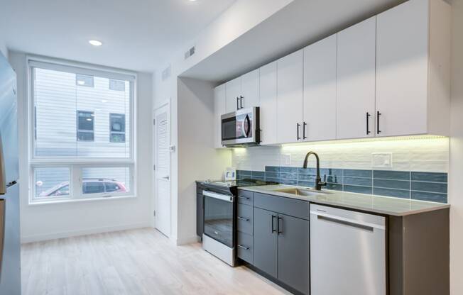 an empty kitchen with white cabinets and a window