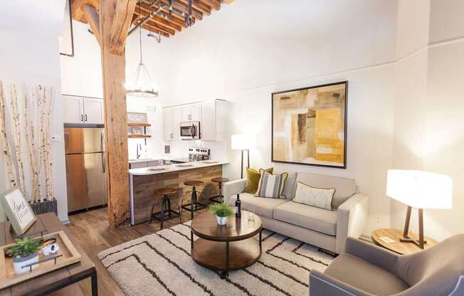 A modern living room with a kitchen in the background.
