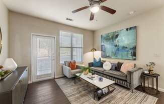 A living room with a grey couch, a coffee table, and a ceiling fan.