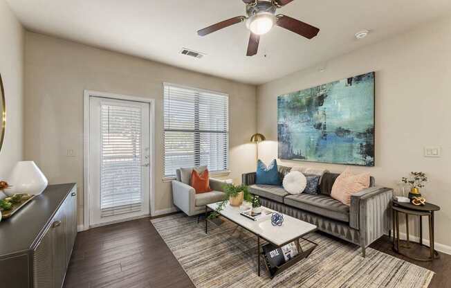 A living room with a grey couch, a coffee table, and a ceiling fan.