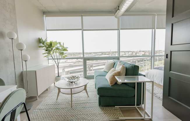 a living room with a green couch and a table    and a window at One Foundry Way, St. Louis, Missouri