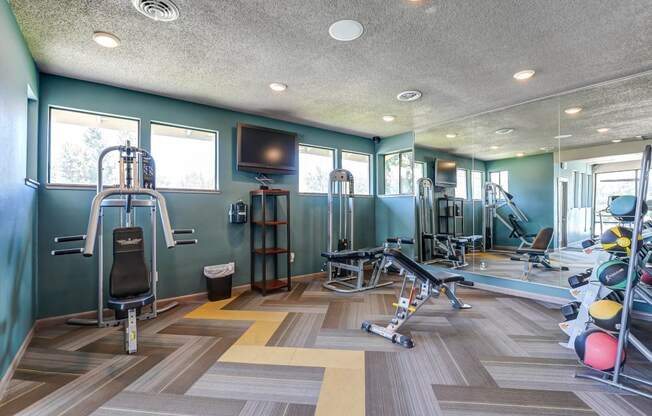 Gym with weights and cardio machines and a tv  at Union Heights Apartments, Colorado Springs, CO