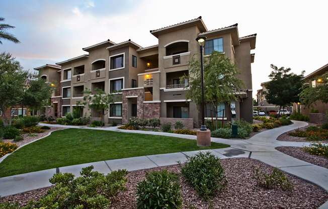 a large apartment building with a sidewalk and grass yard