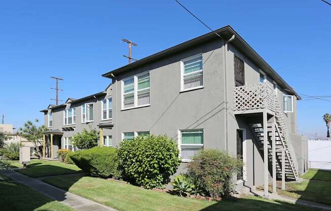 A grey house with a green bush in front.
