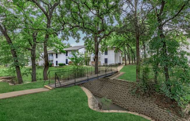 a walkway through the trees at the whispering winds apartments in pearland, tx