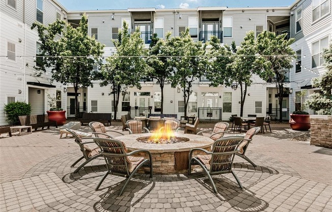 a patio with a fire pit and a building in the background