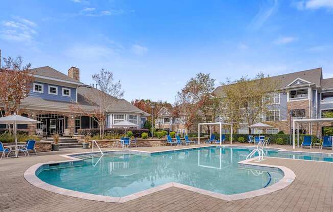 A large swimming pool surrounded by a brick patio and lounge chairs.