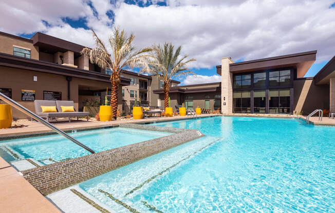 A large swimming pool in front of a building with palm trees.