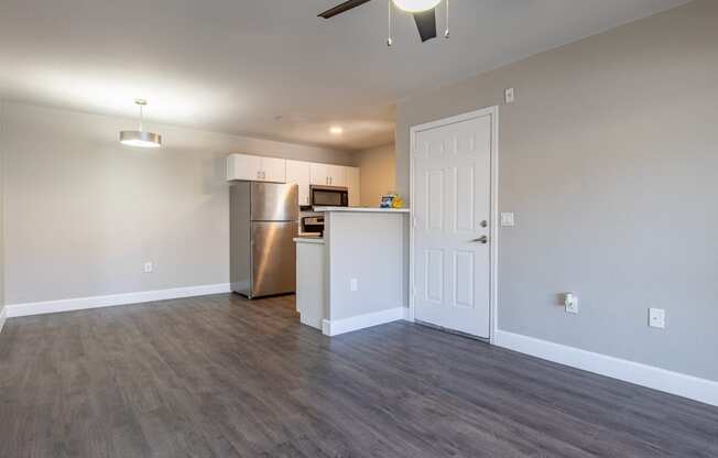 a living room with a ceiling fan and a kitchen in the background