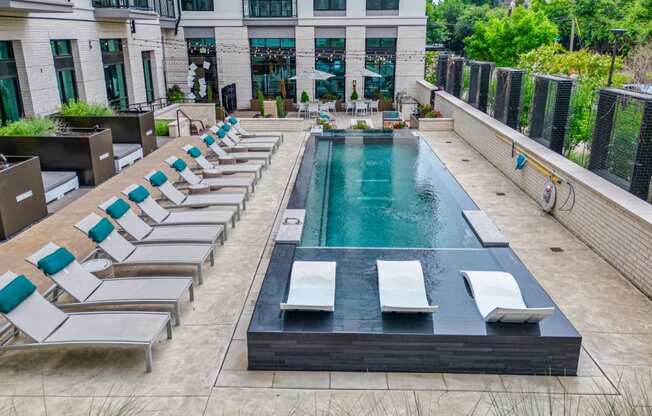 a pool with lounge chairs and a building in the background