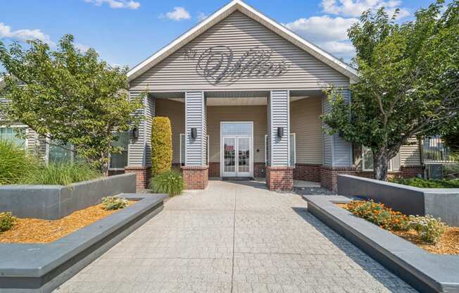 the front of a building with a walkway and a sign