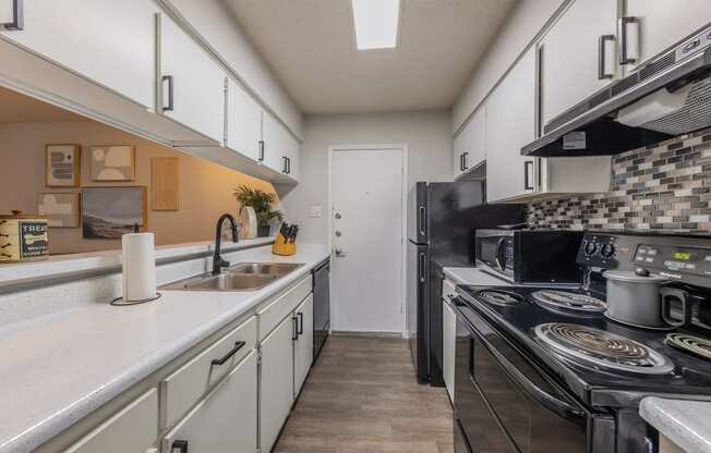 a kitchen with white cabinets and black appliances