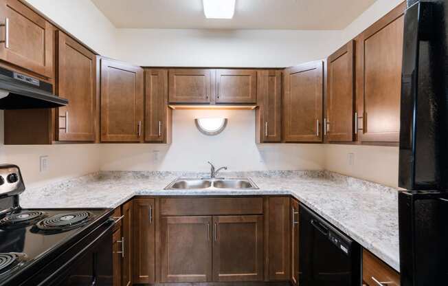 an empty kitchen with wooden cabinets and granite counter tops. Moorhead, MN South Park Apartments
