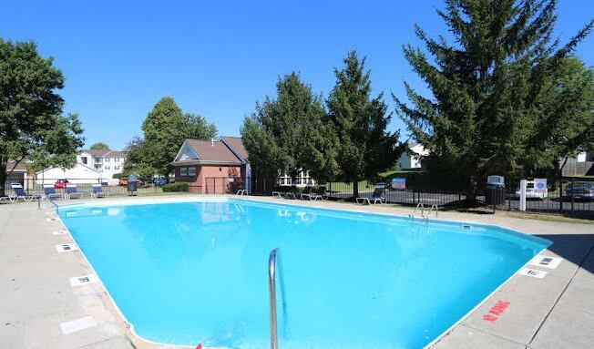 a large swimming pool with trees in the background