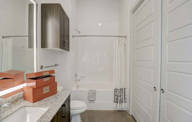 A bathroom with a toilet, sink, and shower at Infinity on the Point Apartments, Dallas 75243