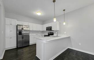 an empty kitchen with white cabinets and a stainless steel refrigerator