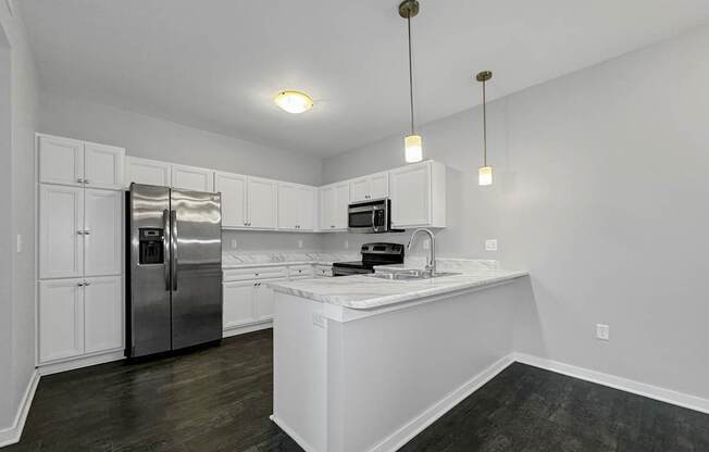 an empty kitchen with white cabinets and a stainless steel refrigerator