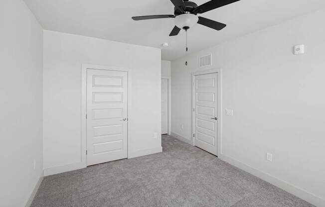 A room with a ceiling fan and two doors.