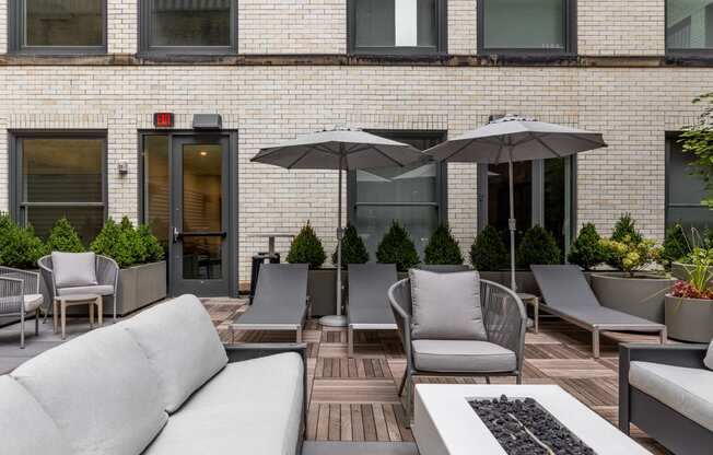 a patio with couches chairs and umbrellas in front of a brick building at The Commonwealth Building, Pittsburgh, 15222