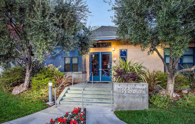 A building with a driveway and a sign that says at The Woods Apartments, California, 95136