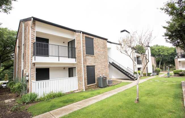 the exterior of an apartment building with a lawn and a staircase