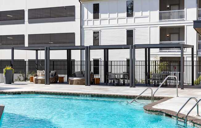 A pool area with a black fence and a white building in the background.