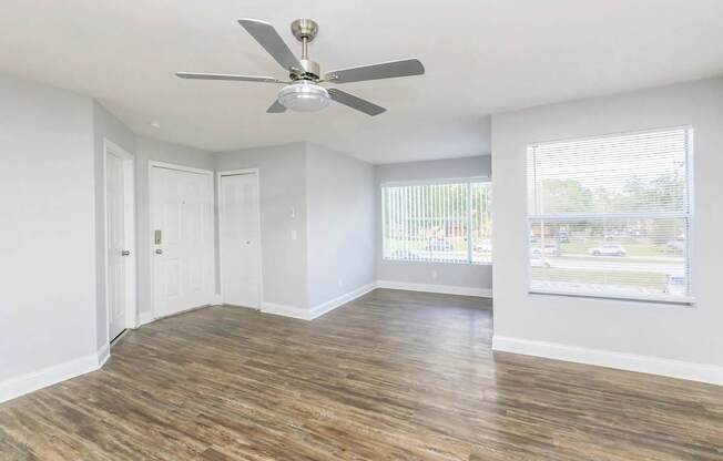 A room with a ceiling fan and wooden flooring.